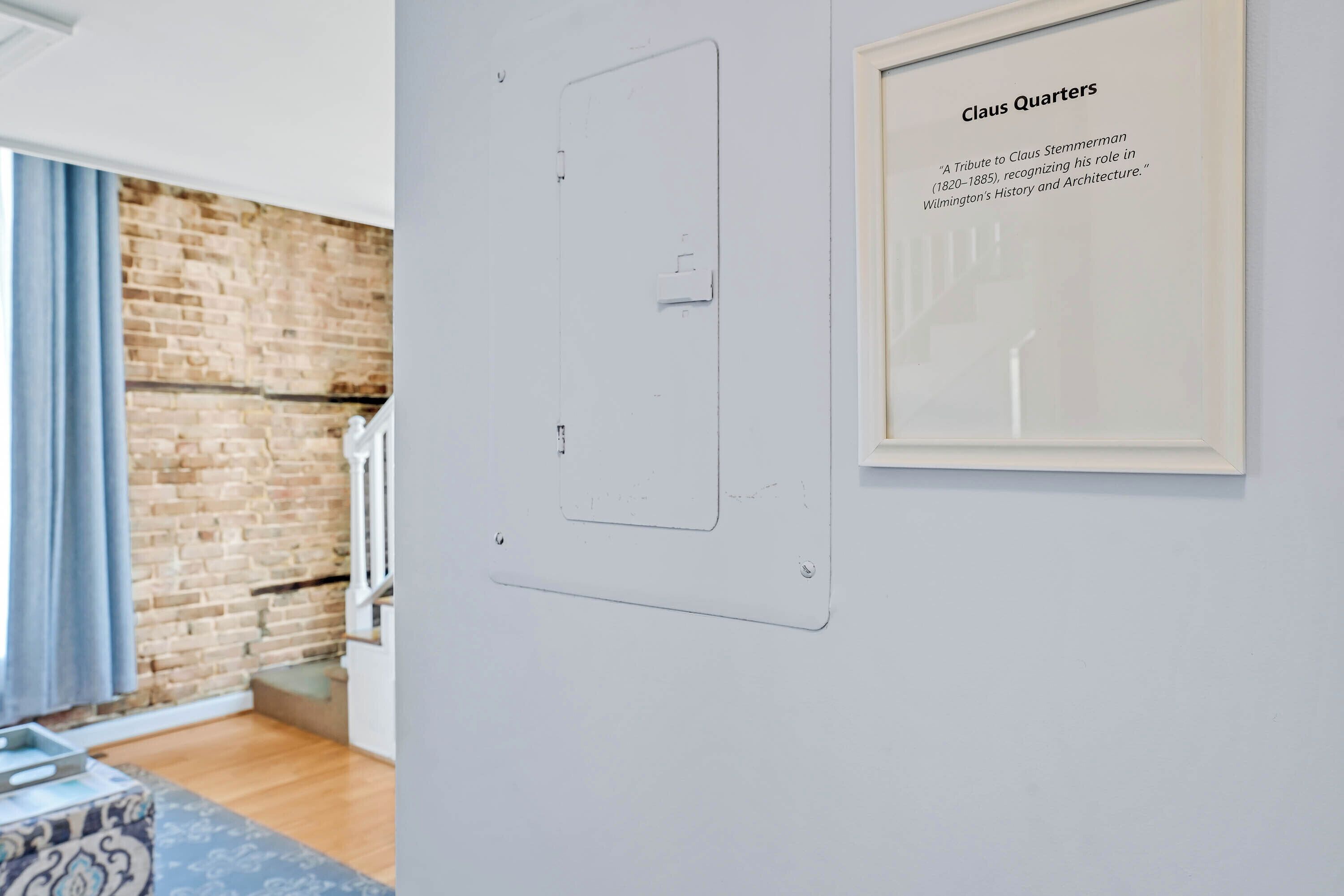 Un texto enmarcado en una pared, una puerta con interruptor de luz y una pared de ladrillo.