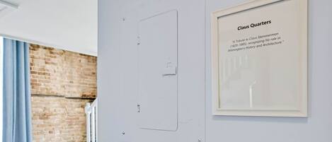 Un texto enmarcado en una pared, una puerta con interruptor de luz y una pared de ladrillo.