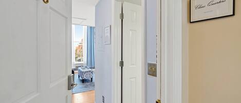 A hallway with a door labeled "Claus Quarters," a blue and white patterned sofa, and a view of the outside.