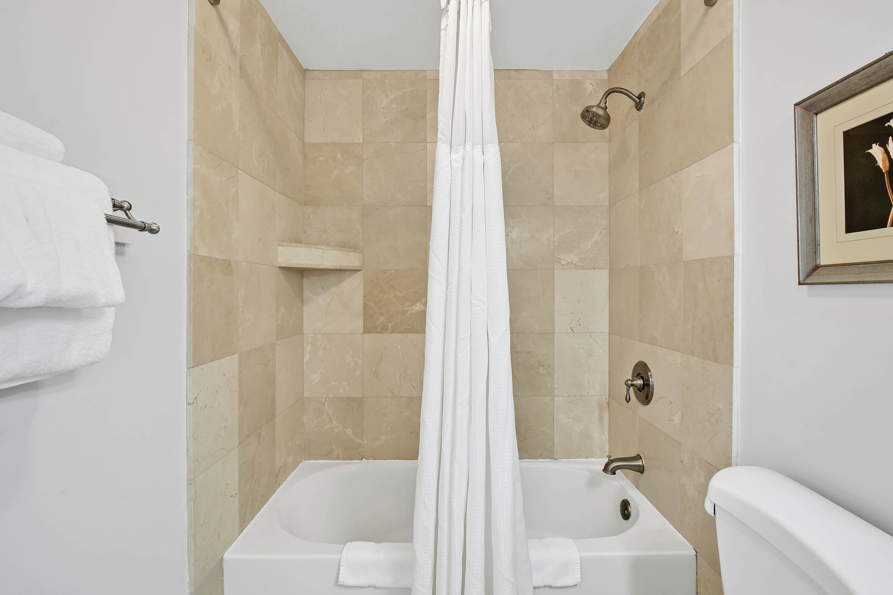 A modern bathroom with a bathtub, shower, and toilet.