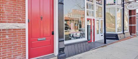 A red door, a window with a view, and a street sign.