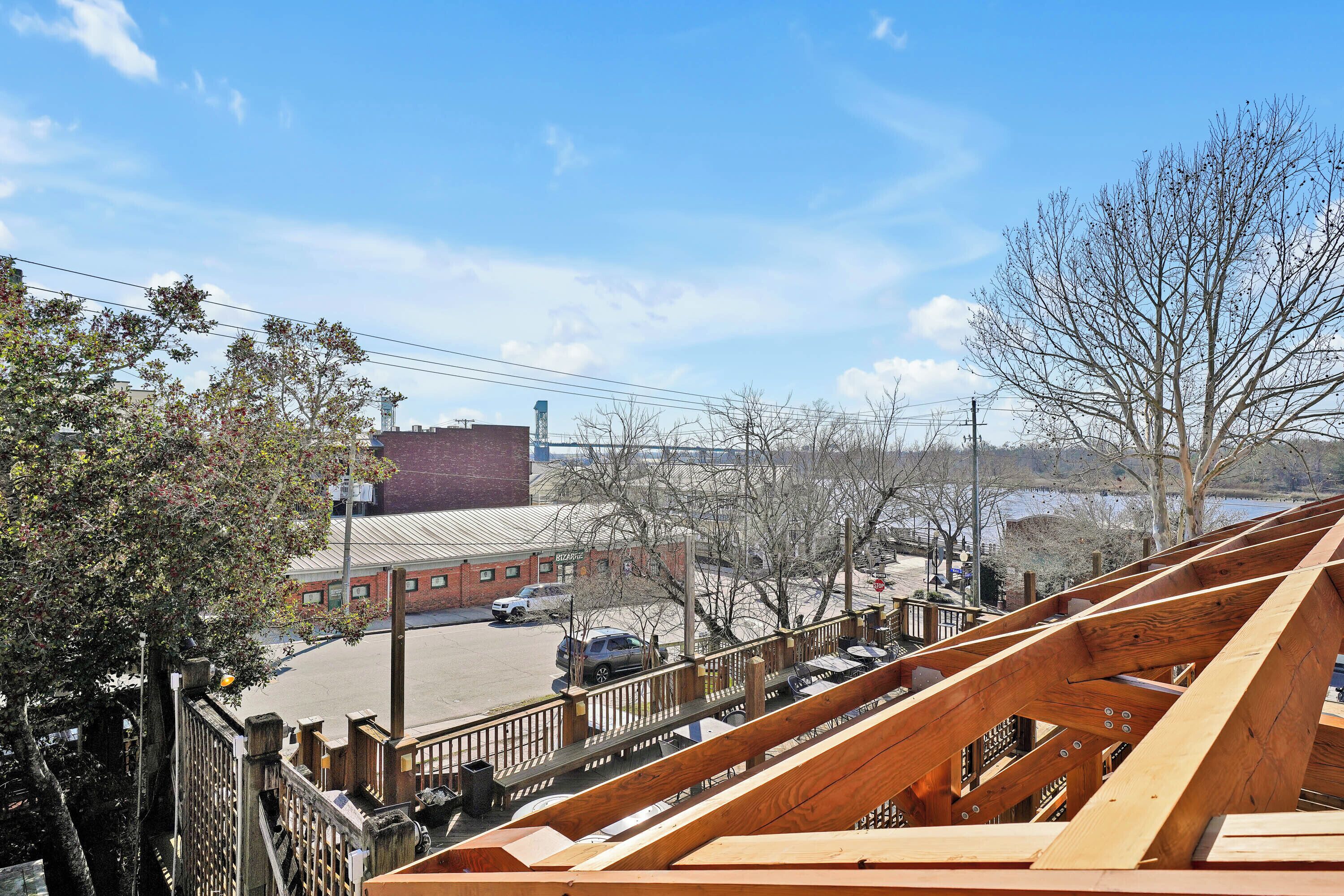 A view from a bridge with a wooden railing, a parking lot, and buildings in the background.