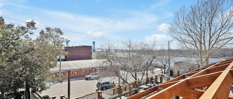 A view from a bridge with a wooden railing, a parking lot, and buildings in the background.