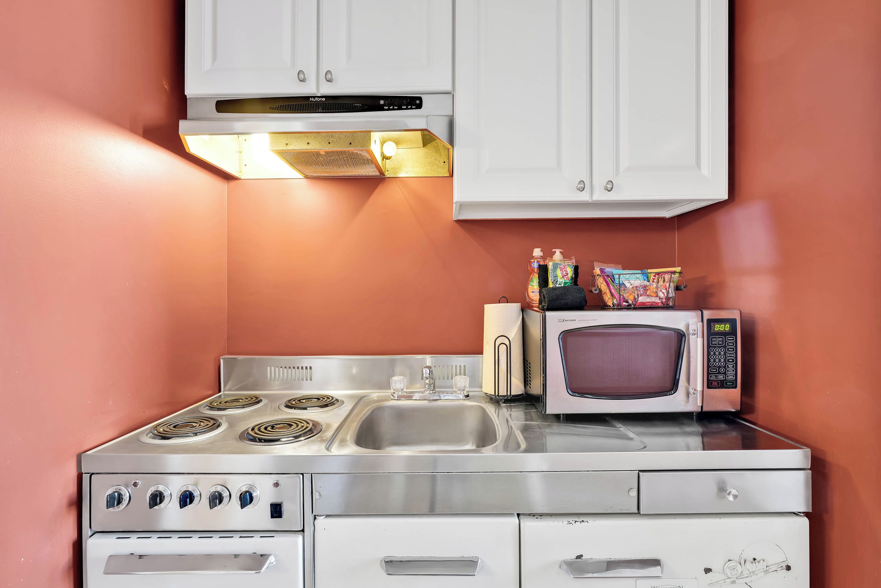 A compact kitchen with a stove, microwave, and sink.