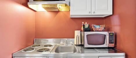 A compact kitchen with a stove, microwave, and sink.