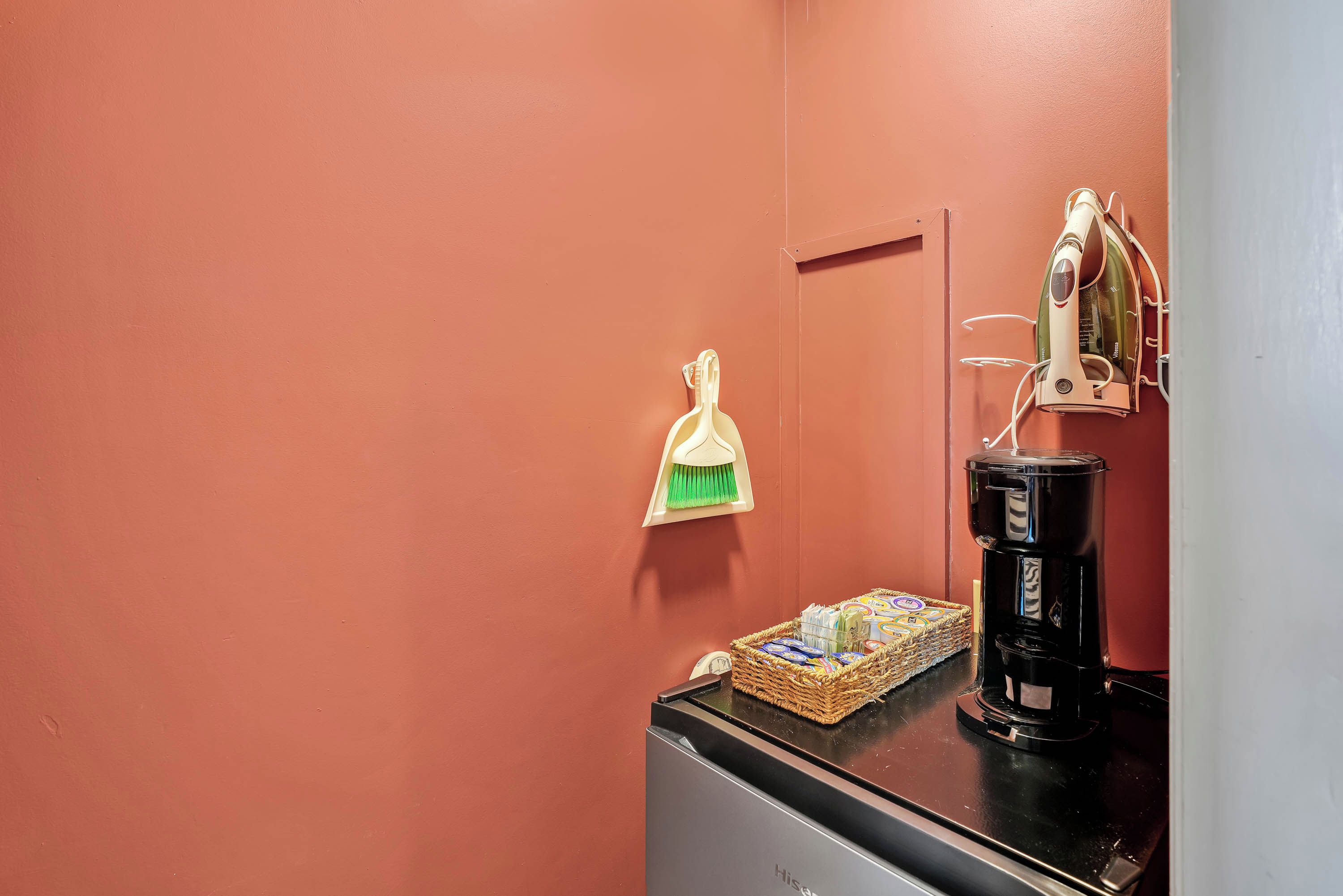 Eine Küchenzeile mit einer Kaffeemaschine, einer Snackauswahl und einem Besen an der Wand.