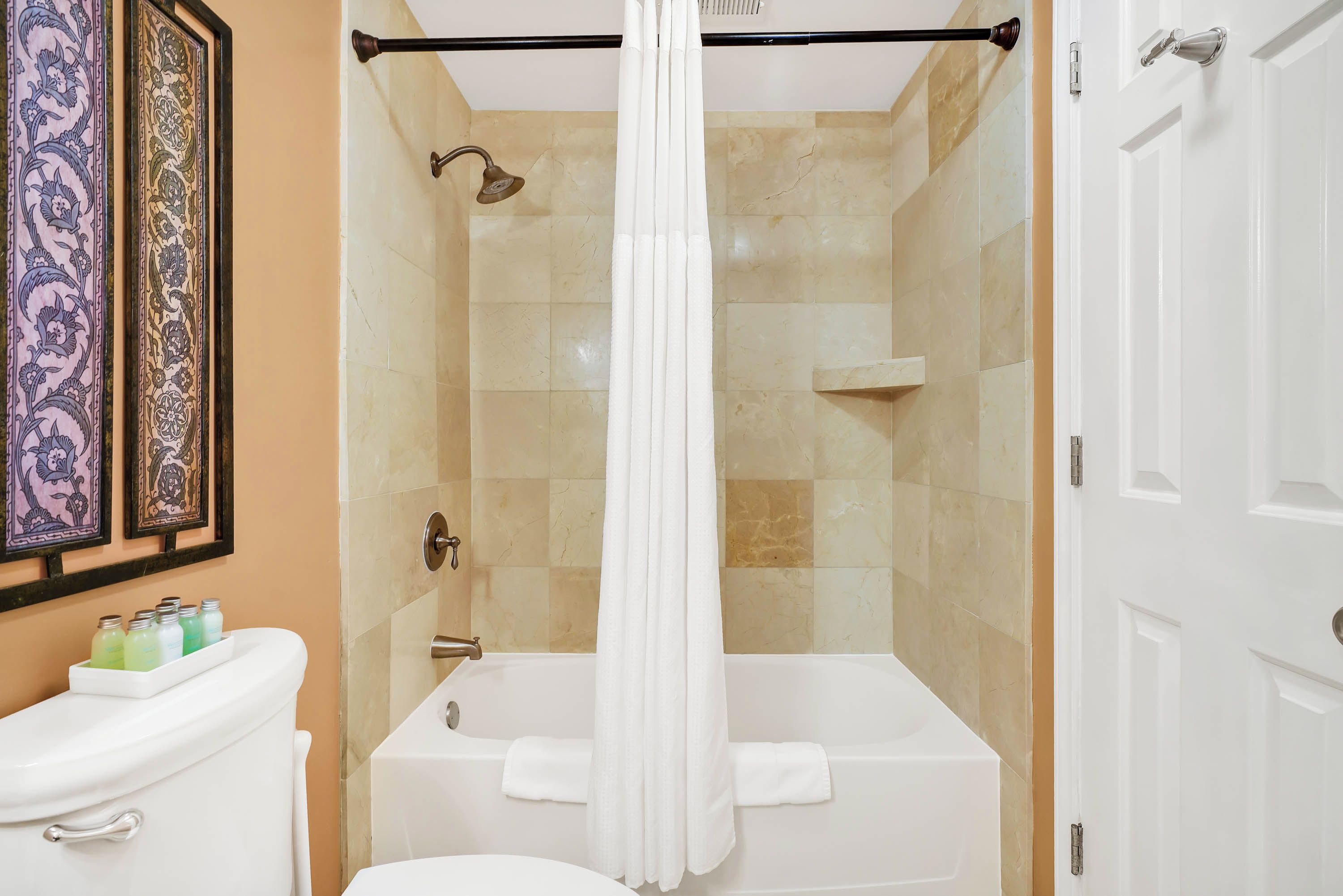 A bathroom with a bathtub, toilet, and shower curtain.
