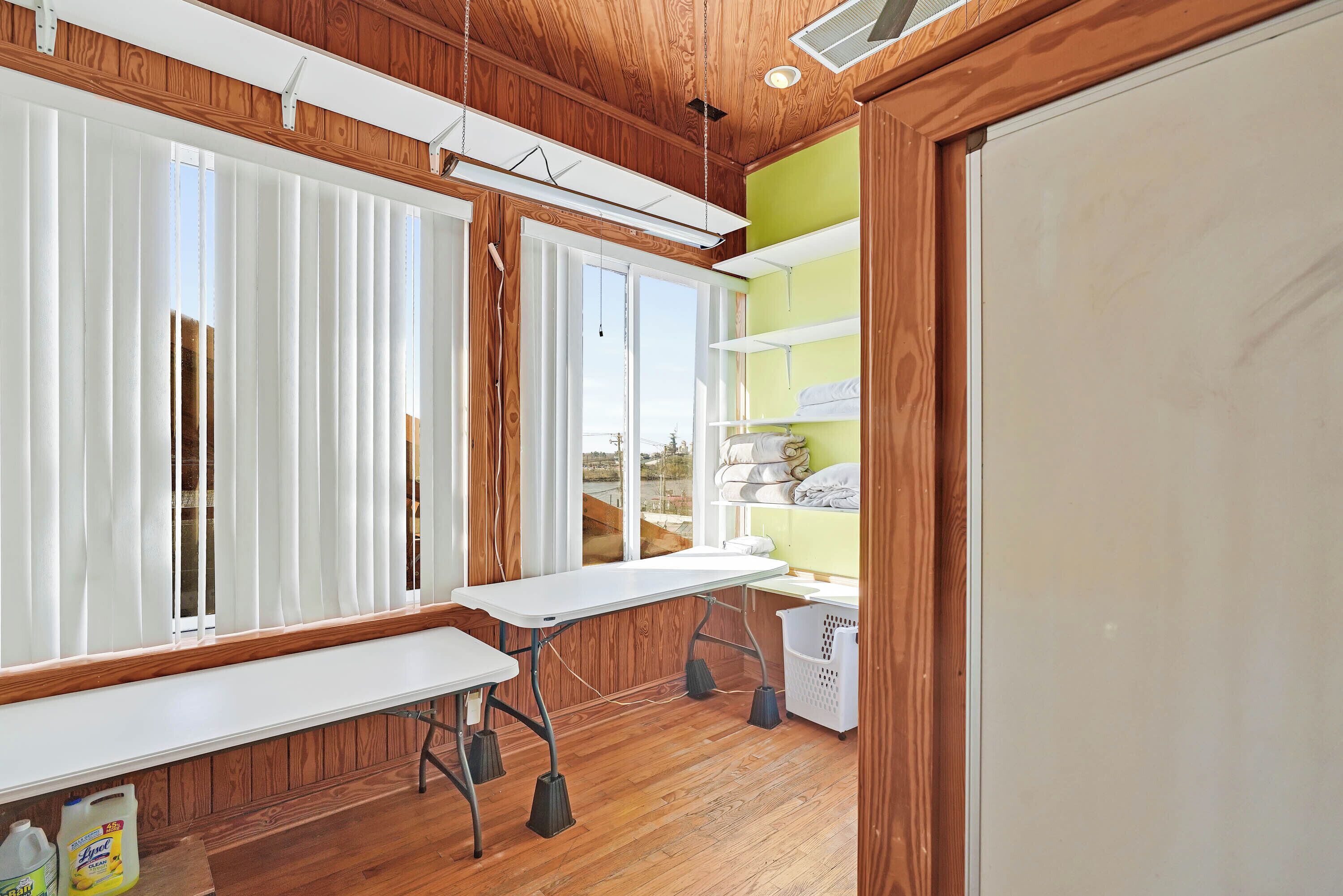 A room with a wooden floor, a white table, and a green shelf unit.