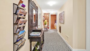 A hallway with a bookshelf, a mirror, and a door leading to another room. - Stemmerman Suite on Front! Perfect location in the Heart of Downtown! (wilmington)