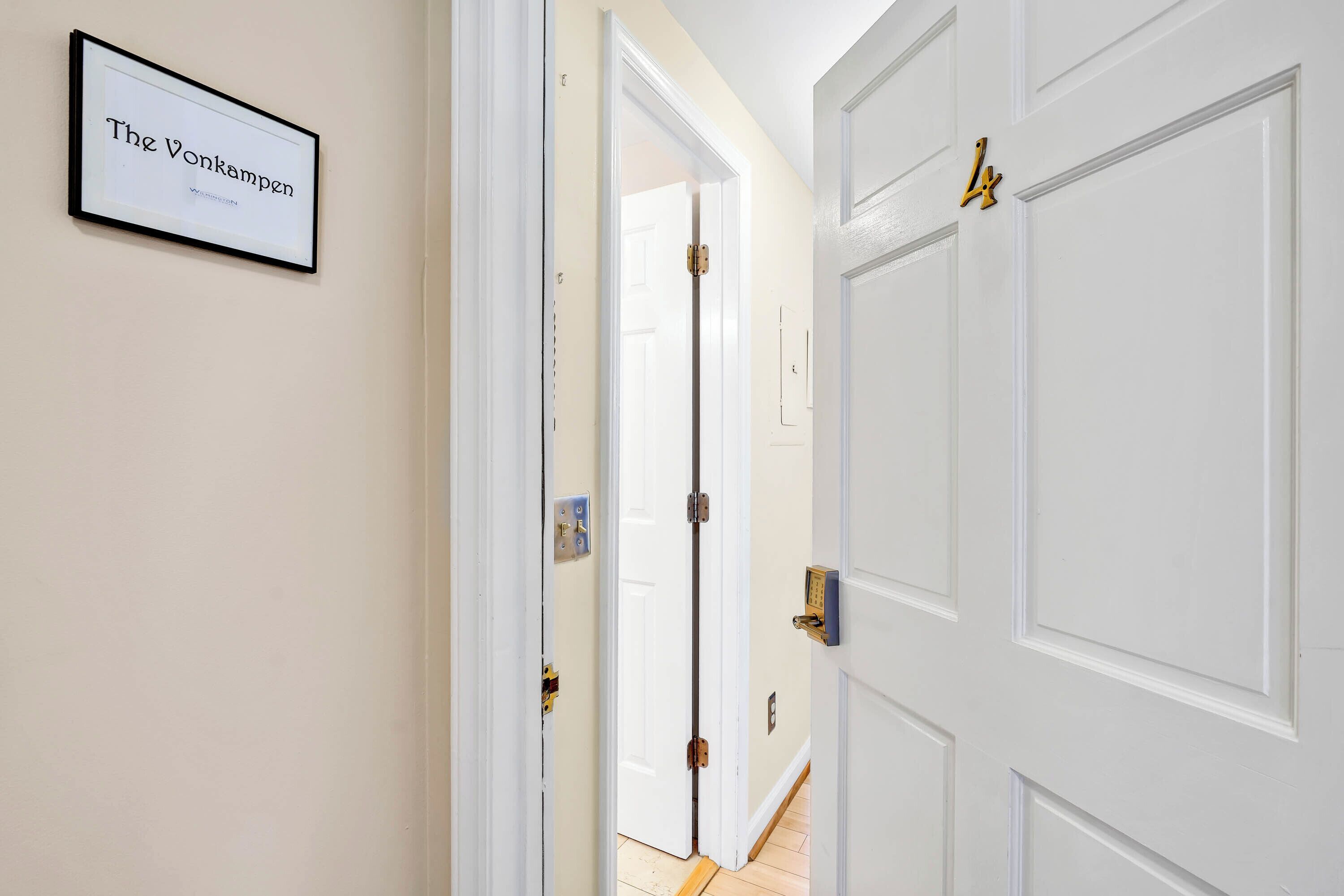A hallway with white doors, a framed sign on the wall, and a doorbell.