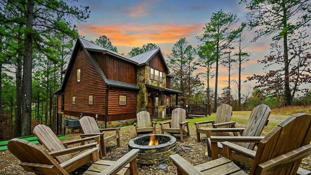 A log cabin with a fire pit and Adirondack chairs in a forest setting. - Heaven Sent - Sauna & Jacuzzi - Mini Golf (Broken Bow)