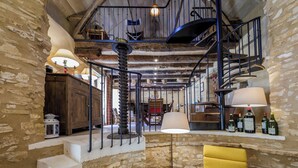 A rustic interior with a spiral staircase, stone walls, and a bar area with bottles. - Exceptional PIGEONNIER in Périgord (Saint-Germain-des-Prés)