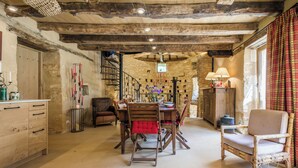 A rustic interior with a wooden dining table, chairs, and a spiral staircase. - Exceptional PIGEONNIER in Périgord (Saint-Germain-des-Prés)