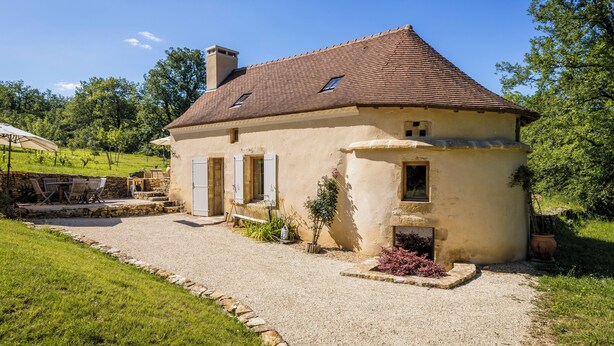 A single-story house with a sloped roof, a gravel driveway, and a stone wall. - Exceptional PIGEONNIER in Périgord (Saint-Germain-des-Prés)