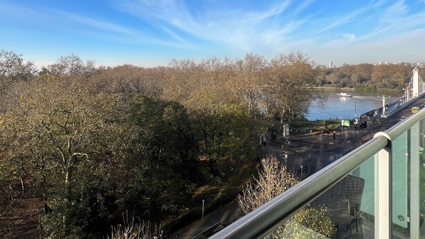 Une vue depuis un balcon donnant sur une rivière, des arbres et un pont.