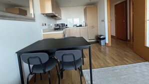 Une cuisine moderne avec des meubles de rangement en bois, une table à manger avec des chaises et une poubelle.