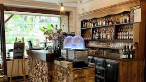 A bar area with a wooden counter, a menu board, and a variety of bottles on shelves. - Hotel du Roy (Aisey-sur-Seine)