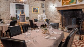 A restaurant with stone walls, a fireplace, and a table set for dining. - Hotel du Roy (Aisey-sur-Seine)