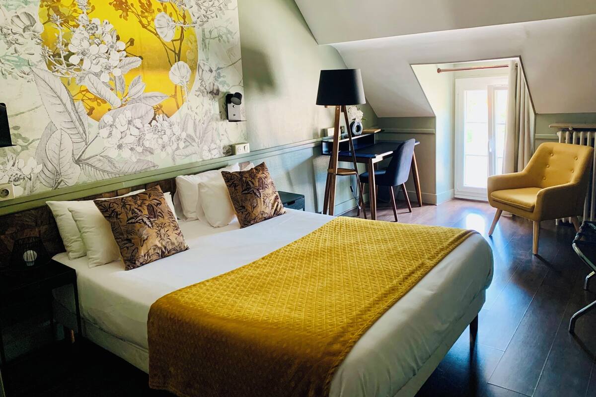 A hotel room with a bed, a desk, and a chair.