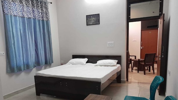 A bedroom with a bed, a wooden table, and two chairs.
