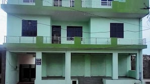 A two-story building with a flat roof, multiple windows, and a staircase leading to the entrance.