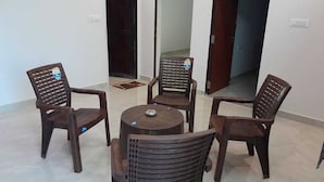 A room with four wooden chairs and a small round table, with doors leading to other areas.