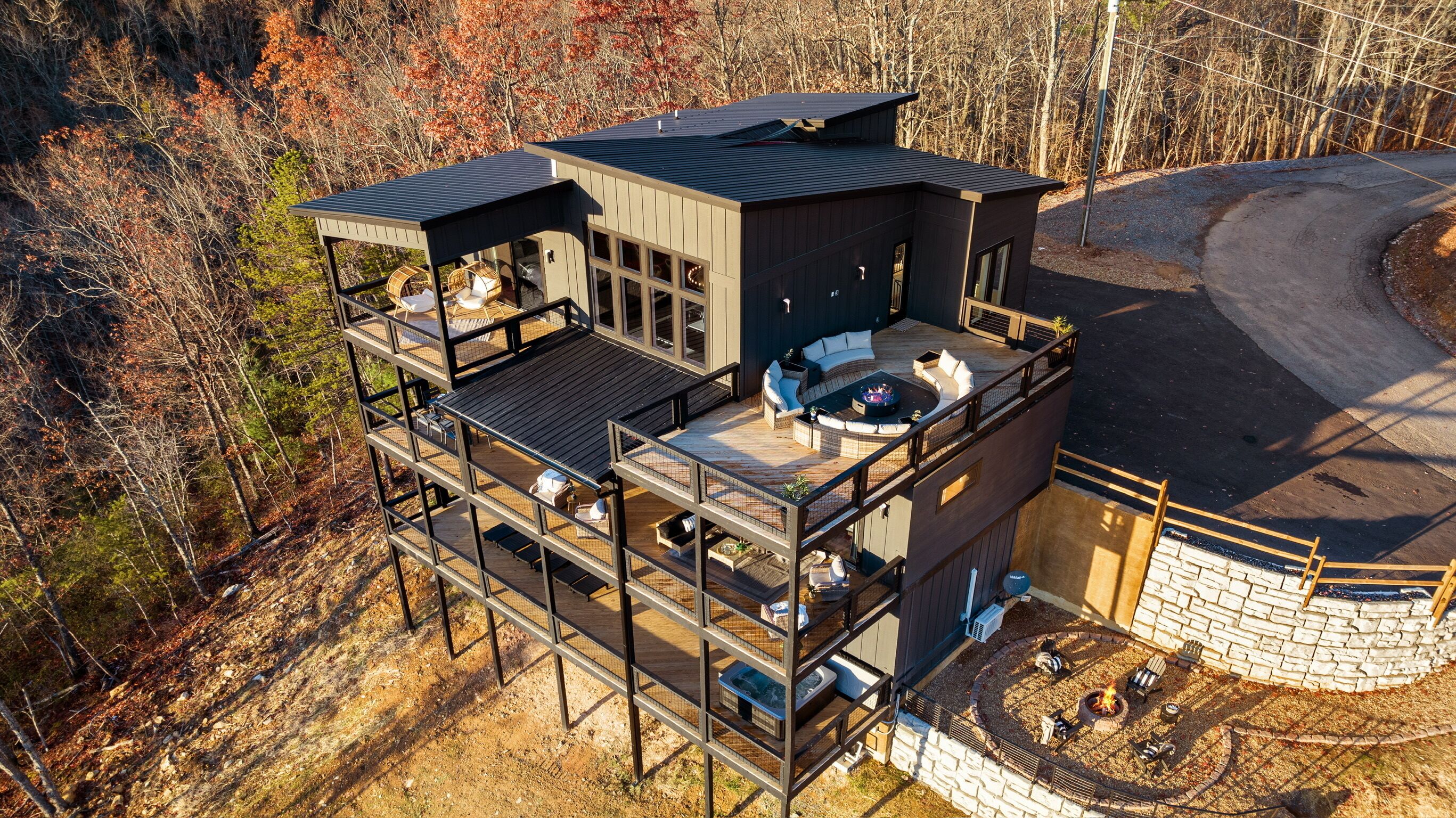 A multi-level cabin with outdoor decks, a fire pit, and a stone wall.
