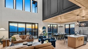 A spacious living area with a large sofa, dining table, and kitchen island. - Stunning View, Modern Cabin in Gatlinburg, Htd Indoor Pool, Hot Tub, Game Room! (Gatlinburg)