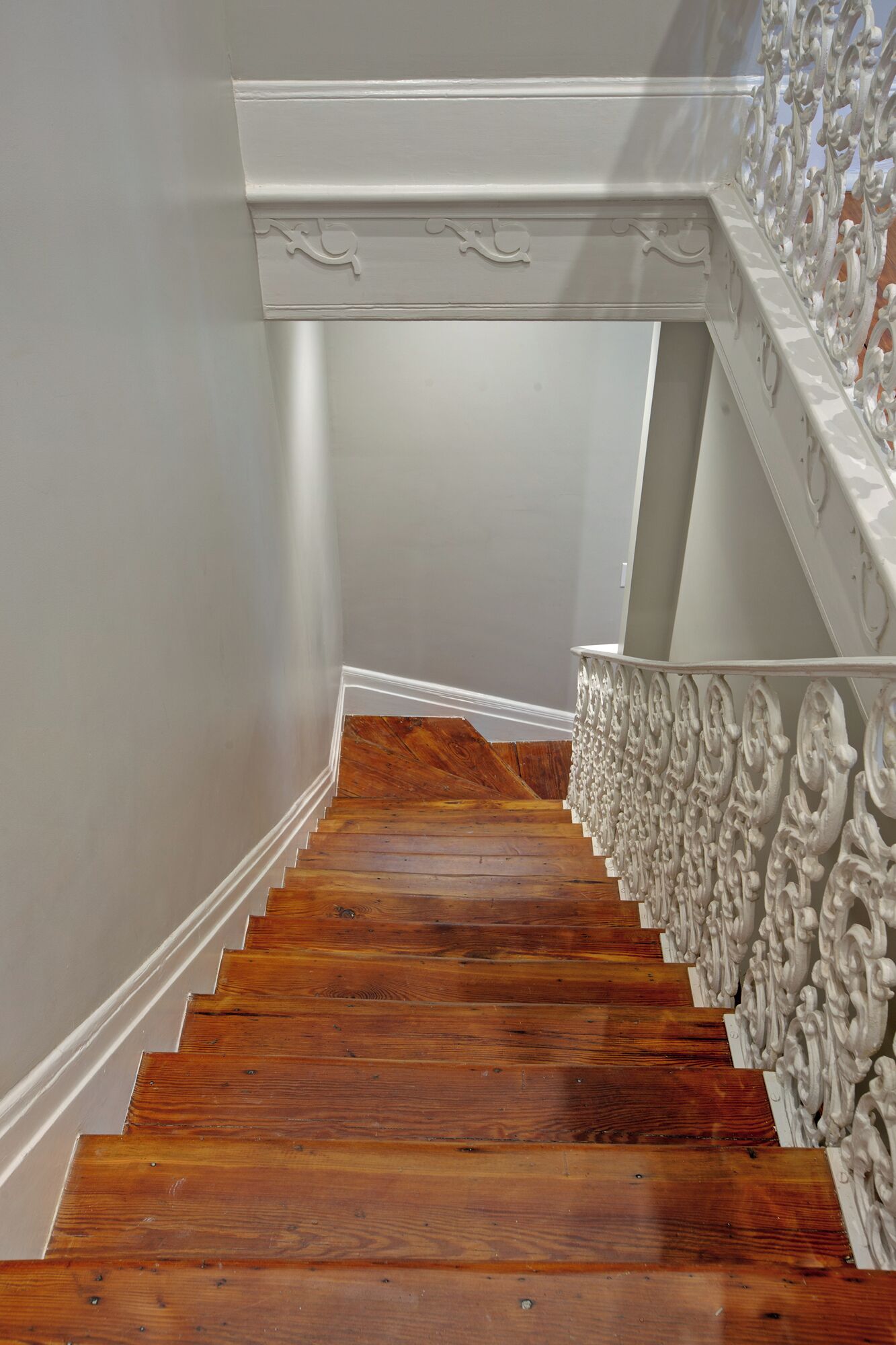 Un escalier en bois, avec des lambris blancs et des balustrades blanches richement décorées.