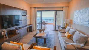 A modern hotel room with a flat-screen TV, a sofa, a coffee table, and a balcony with a view of the sea. - Villa Del Palmar in Loreto, Luxurious Relaxation & Adventure, Resort Life (Loreto , B.C.S)