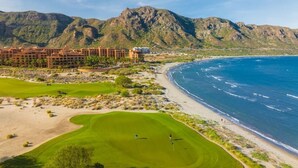 A golf course with a view of the ocean and mountains, a hotel in the background, and a clear sky. - Villa Del Palmar in Loreto, Luxurious Relaxation & Adventure, Resort Life (Loreto , B.C.S)