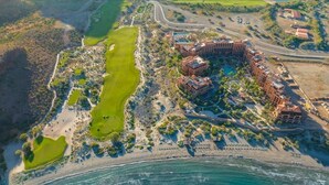 An aerial view of a coastal resort with multiple buildings, a golf course, and a beach. - Villa Del Palmar in Loreto, Luxurious Relaxation & Adventure, Resort Life (Loreto , B.C.S)