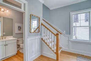 Staircase leads to an upper level, with a large mirror and cabinet below.