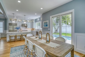 Enjoy meals in the kitchen with stainless steel appliances and a central island, then dine at the wooden table with views of the backyard and pool.