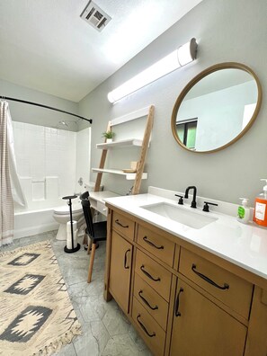 A bathroom with a white sink, wooden cabinets, a mirror, and a shower curtain.
