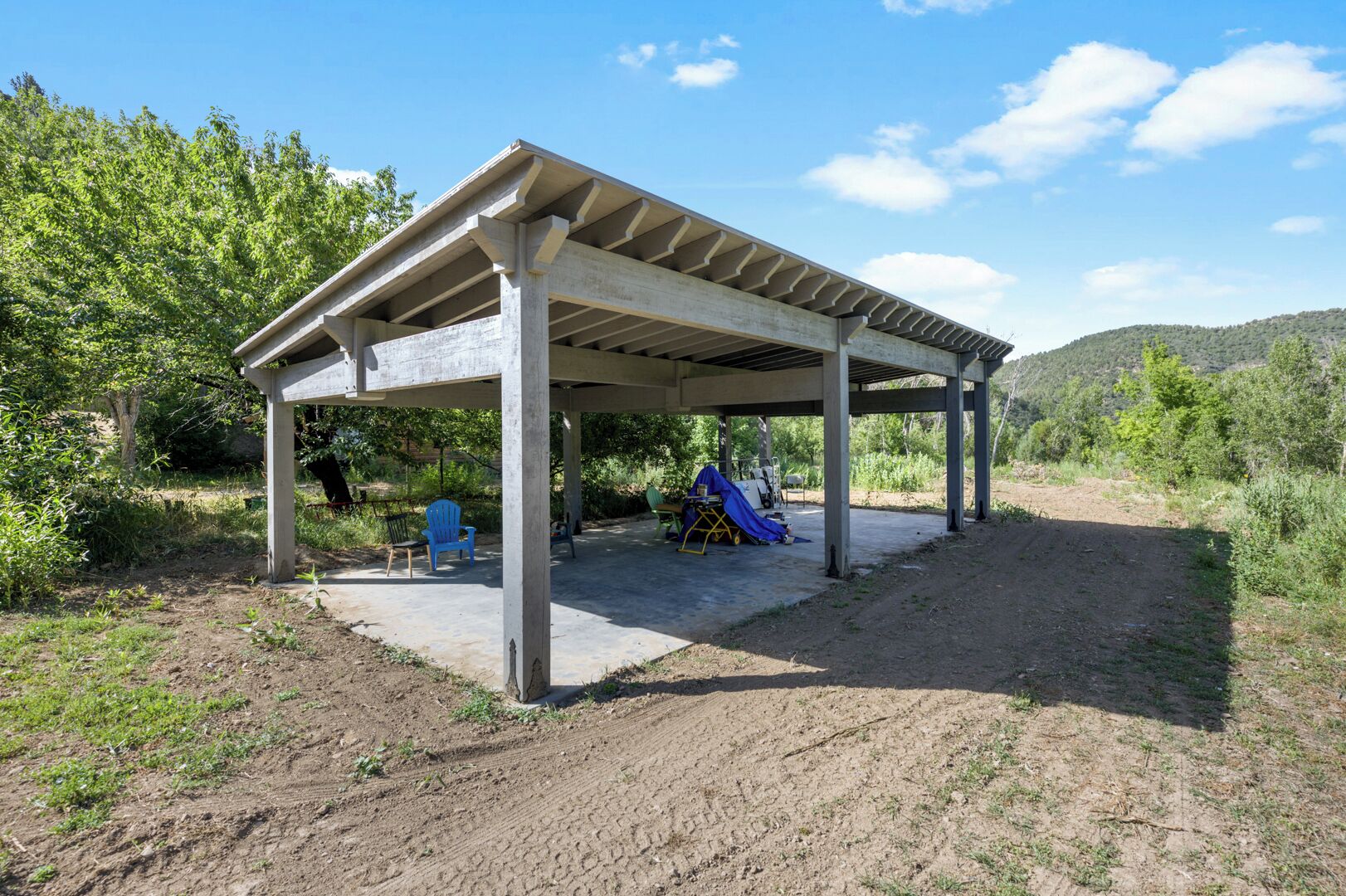 Un espace extérieur abrité, doté d’un sol en béton, d’une chaise bleue et d’un toboggan.