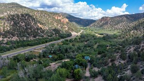 A mountainous landscape with a road, scattered buildings, and dense vegetation.