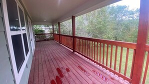 A covered porch with a red railing, a wooden deck, and a view of trees. - Fabulous 3-bedroom house with AC in Cleveland (Cleveland)