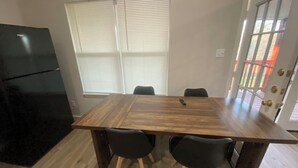 A dining area with a wooden table and four chairs, a black refrigerator, and a window with blinds. - Fabulous 3-bedroom house with AC in Cleveland (Cleveland)