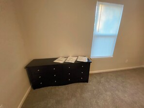 A simple, functional room with a dresser and carpeted floor.