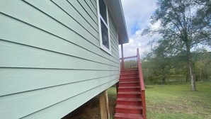 A house with a green exterior and a red staircase leading to the front door. - Fabulous 3-bedroom house with AC in Cleveland (Cleveland)