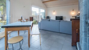 A spacious living area with a dining table, sofa, and television.