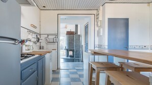 A kitchen with a checkered floor, wooden tables, and a view of a courtyard through an open door.