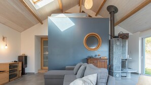 A modern living room with a grey sofa, wooden cabinets, a fireplace, and a skylight.