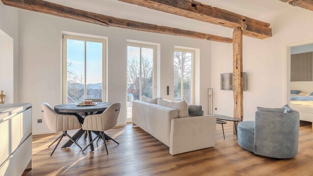 Ein geräumiger Wohnbereich mit Holzboden, einer Couch, einem runden Tisch mit Stühlen und einem Fernseher.