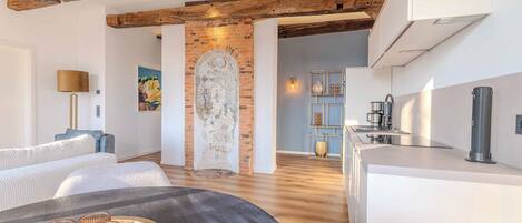 A modern kitchen with a brick wall, wooden beams, and a sleek countertop.