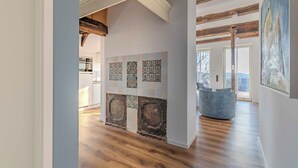 Ein Korridor mit Holzboden, einer mit Zierleisten versehenen Fliesenwand und einem großen Gemälde auf der rechten Seite.