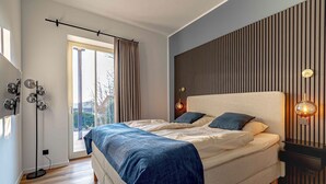 Ein modernes Schlafzimmer mit einem großen Bett, einer Stehlampe und Blick ins Freie.