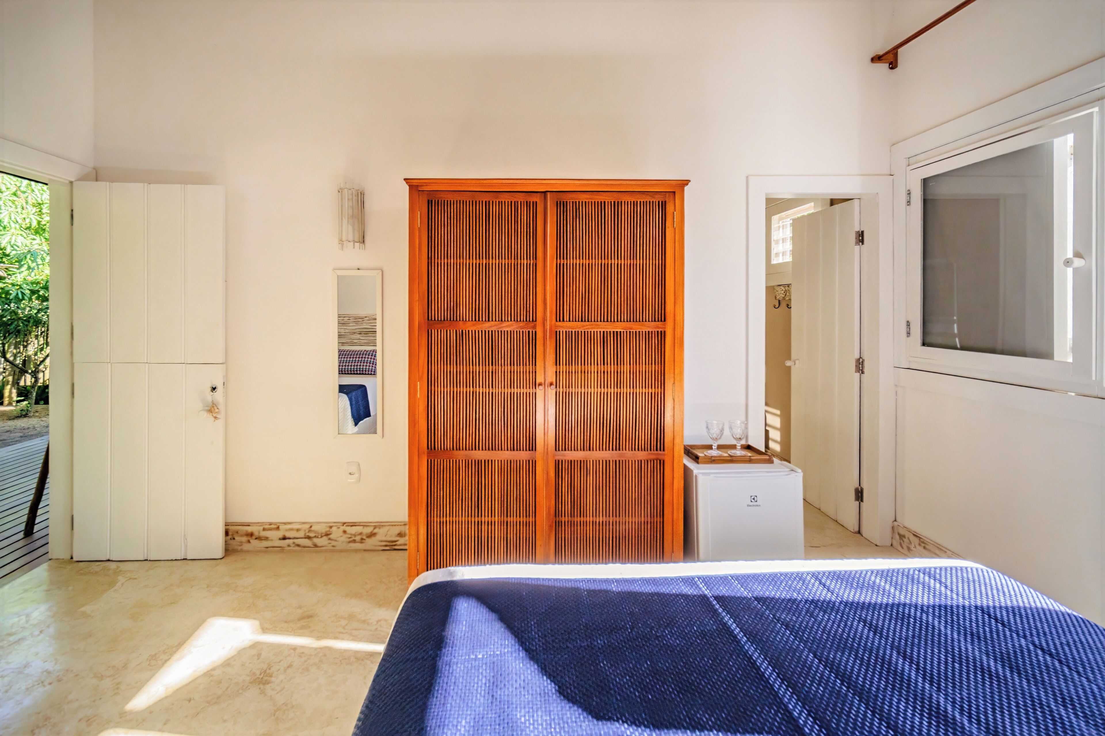 A bedroom with a bed, a wardrobe, a small cabinet, and a window.