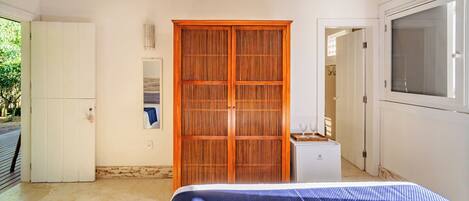 A bedroom with a bed, a wardrobe, a small cabinet, and a window.